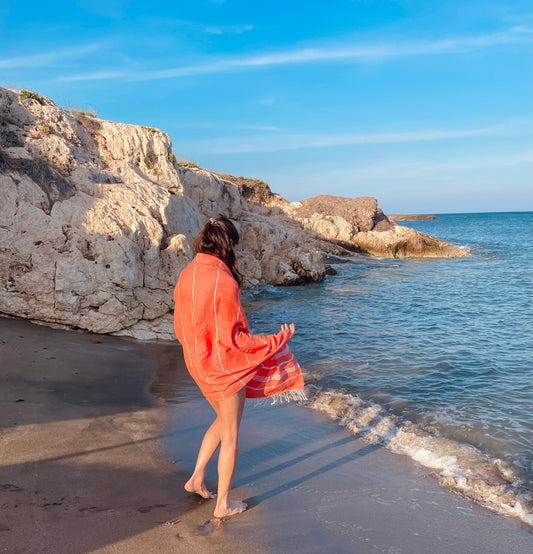 Frau trägt ihr Strandtuch als Pareo am Meer